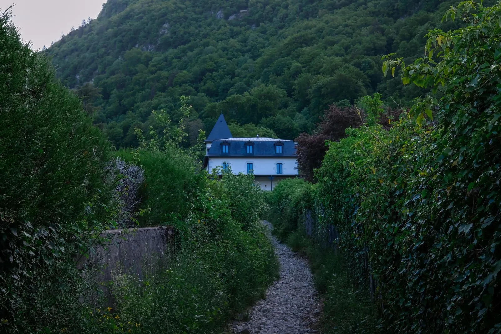 A turreted white villa tucked into a forested hillside at the end of a path