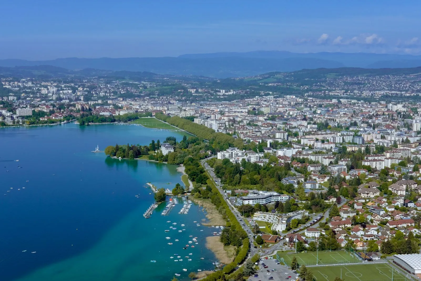 Aerial view of Lake Annecy's turquoise shoreline and the city beyond