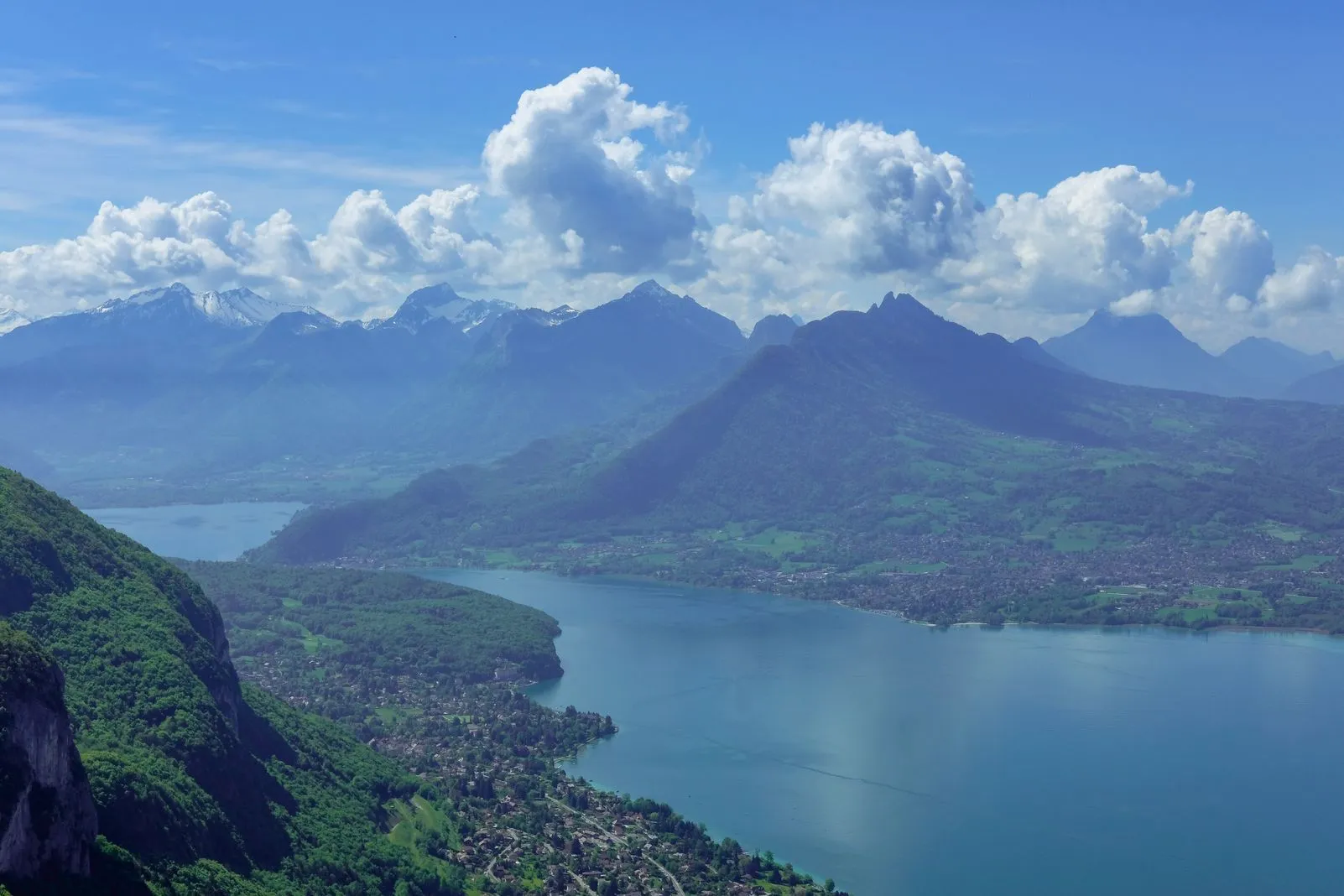 Panoramic view of Lake Annecy winding between mountains and a lakeside town