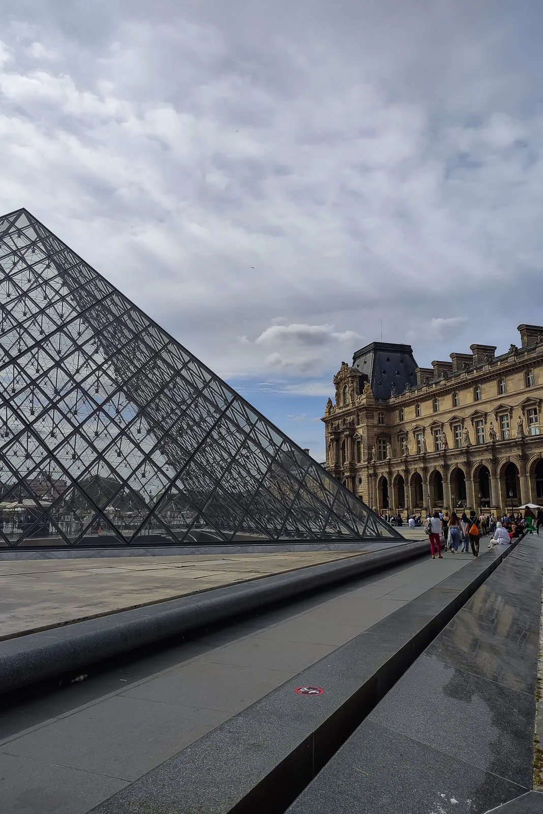 The Louvre's glass pyramid stands before the museum's ornate stone wing