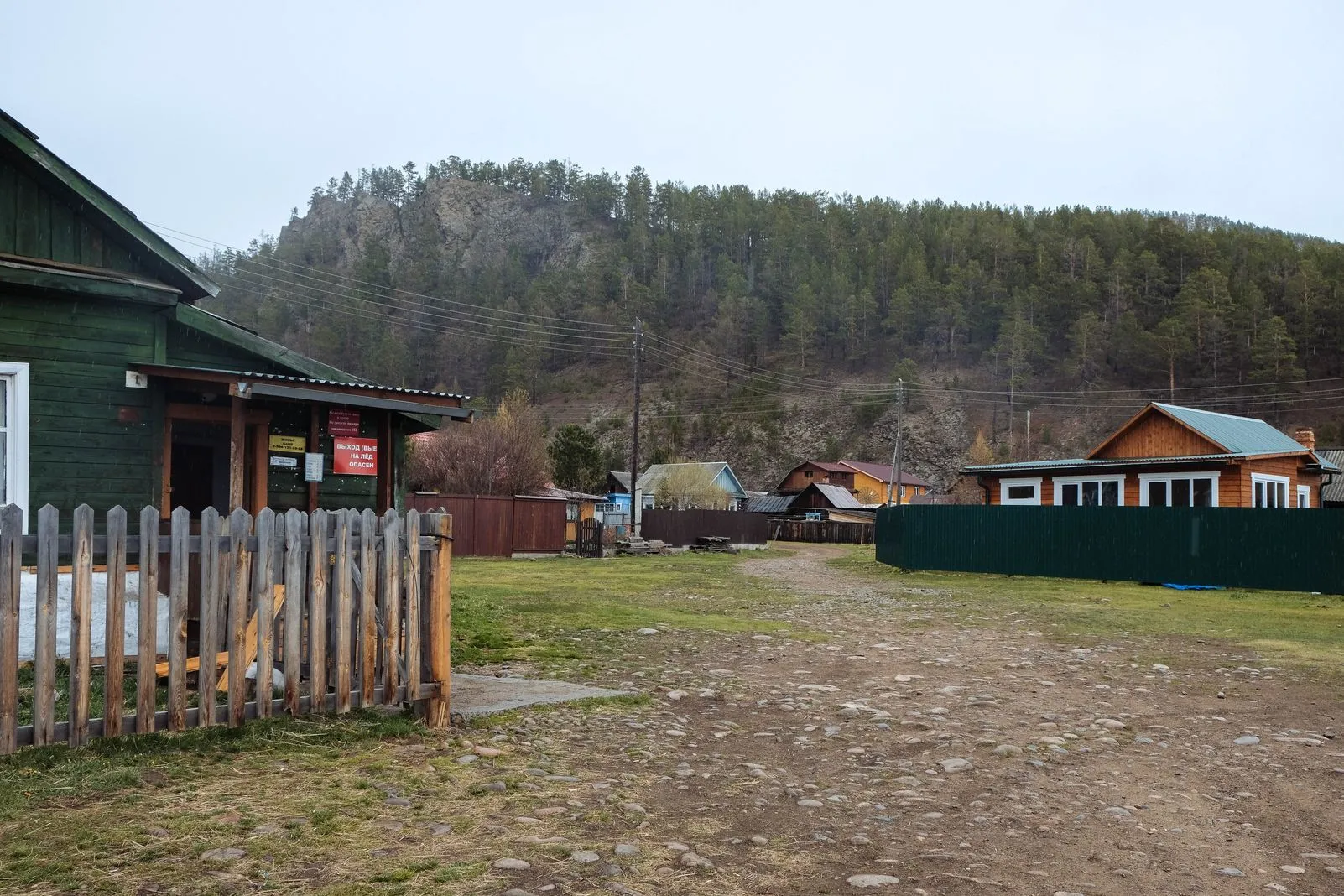 Wooden village houses backed by a forested, rocky hillside