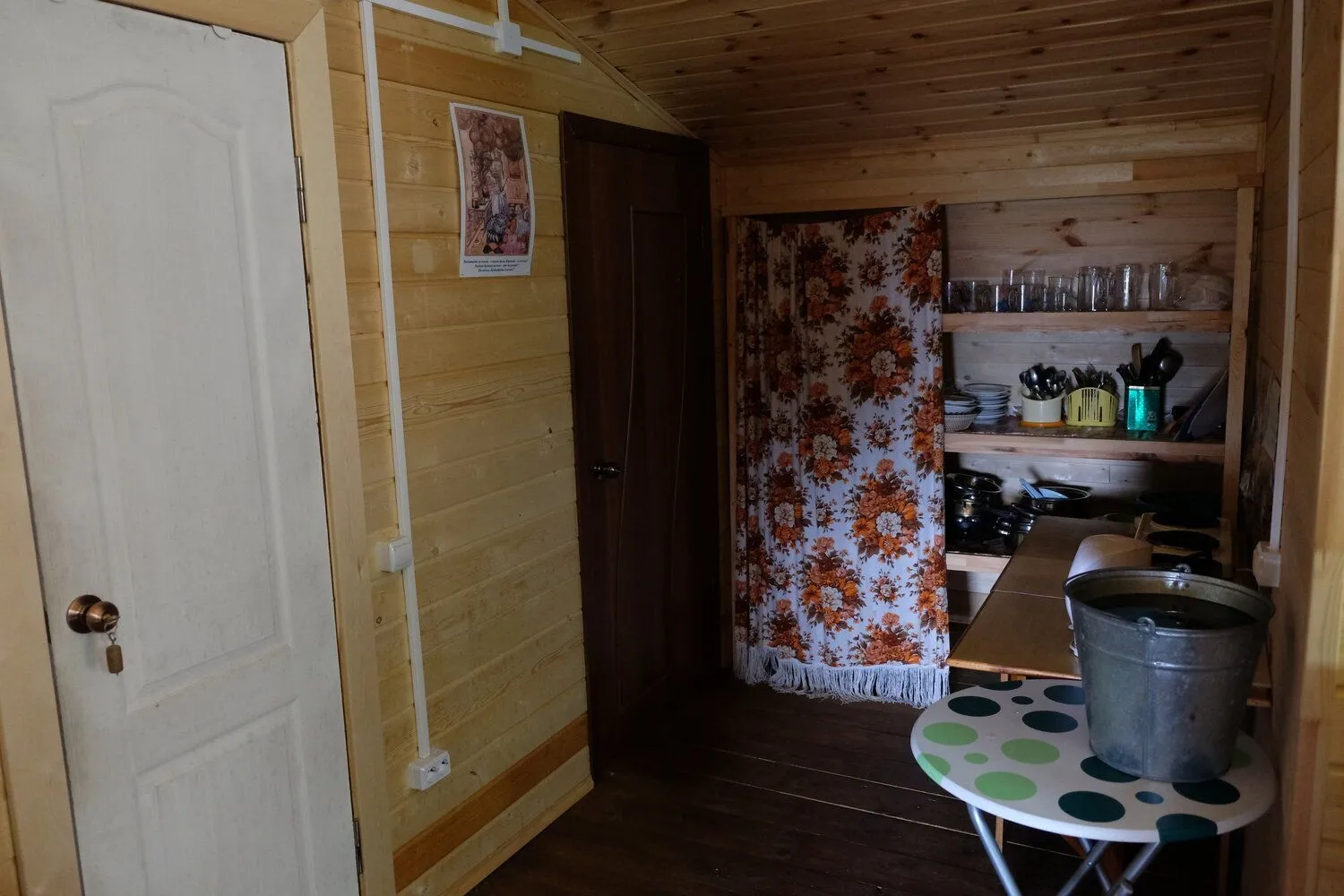 Wood-paneled cabin hallway with a floral curtain and shelved kitchenware