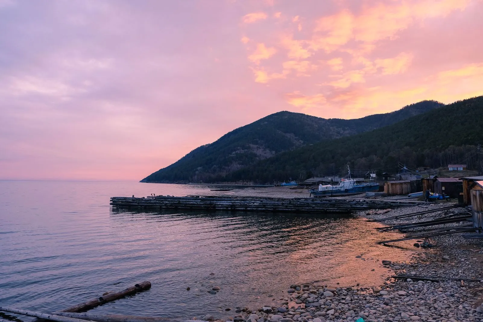 Pink sunset sky over Lake Baikal with a wooden pier and boats