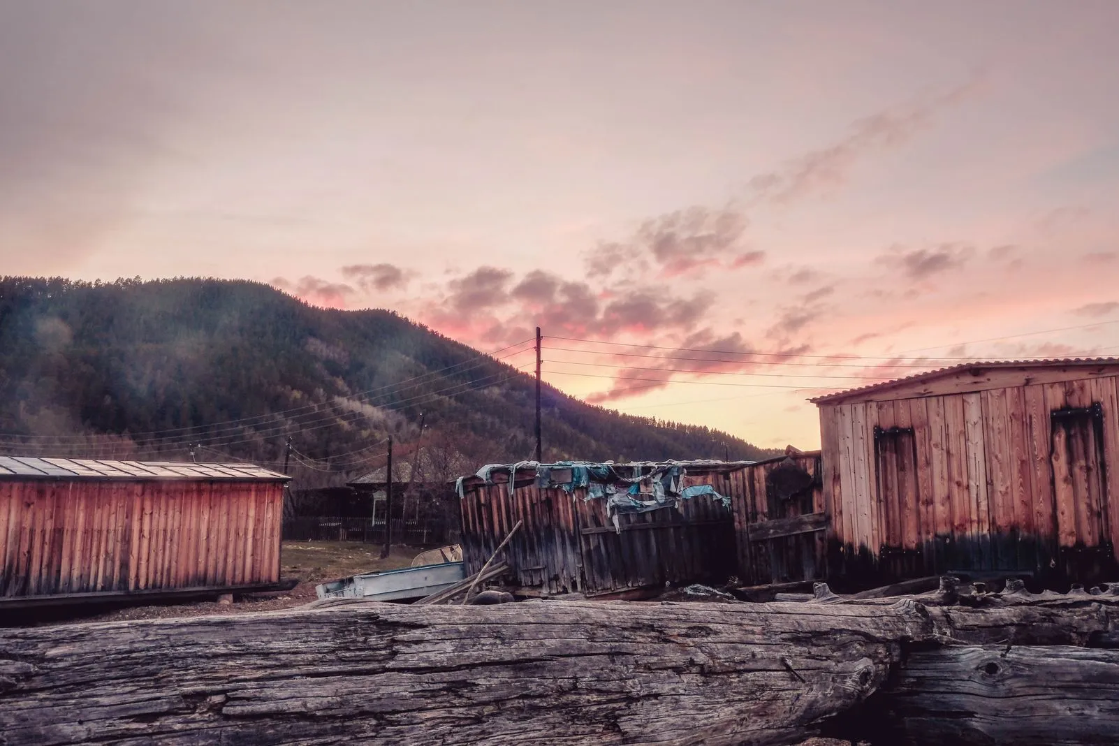 Weathered wooden sheds silhouetted against a pink sunset sky