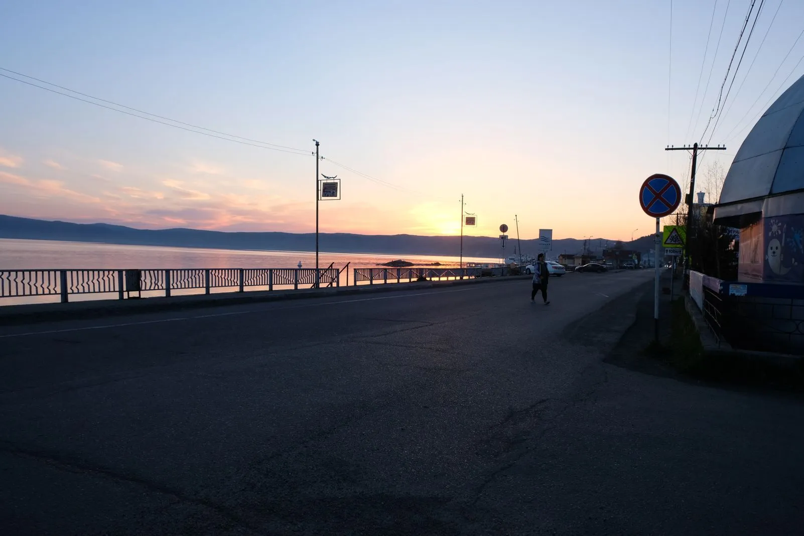 Person crossing a road at sunset along Lake Baikal's waterfront