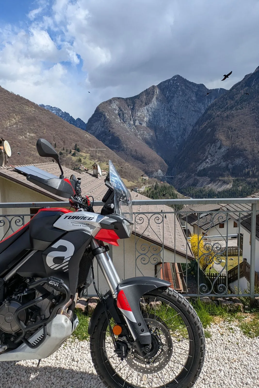 Aprilia Tuareg parked on a terrace with jagged mountain peaks and circling birds behind it