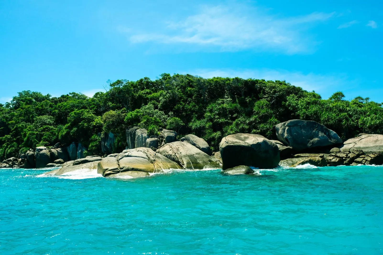 Rocky, tree-covered island outcrop rising from turquoise water