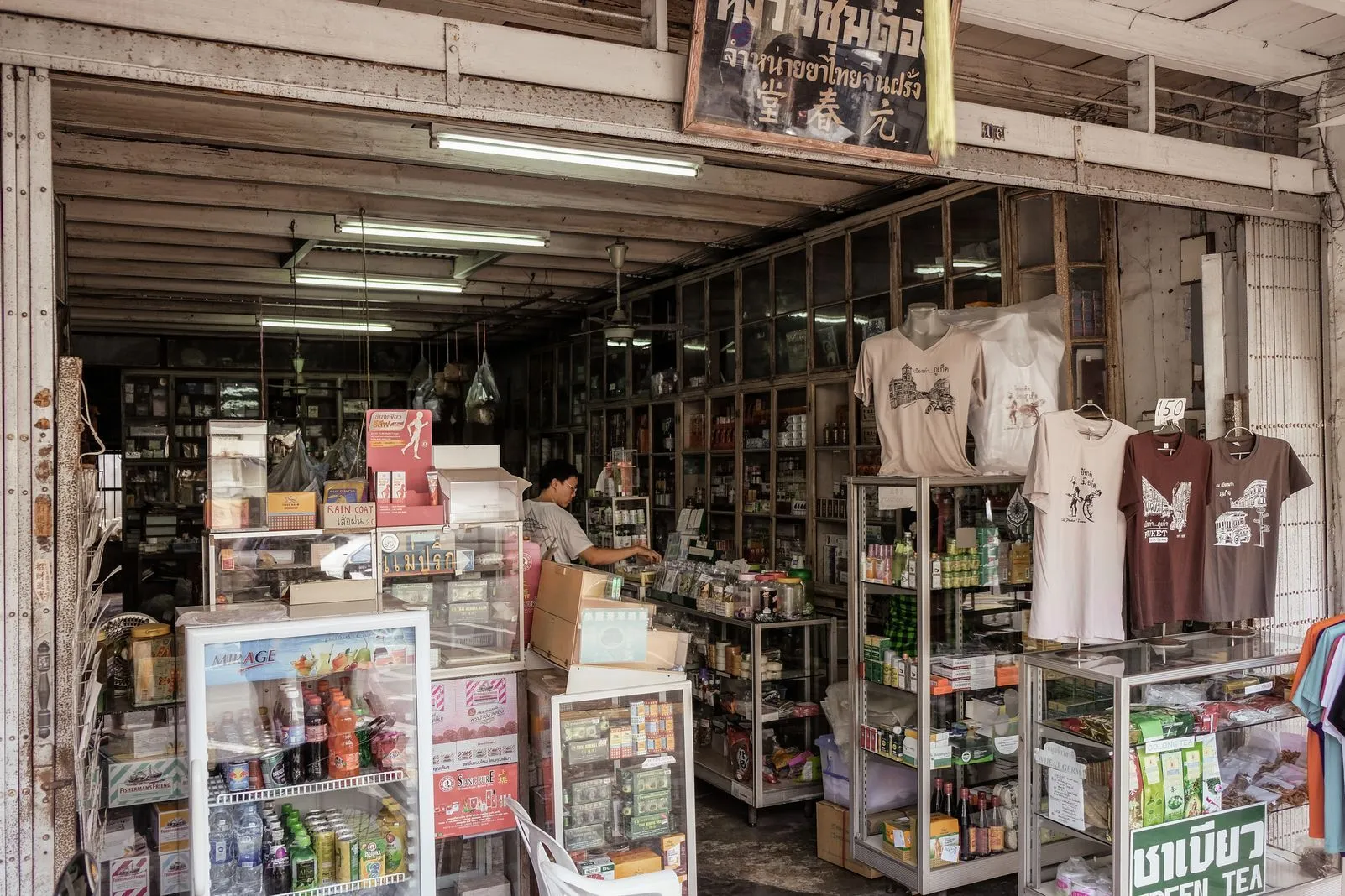 Interior of a traditional general store stocked with goods, drinks, and t-shirts for sale