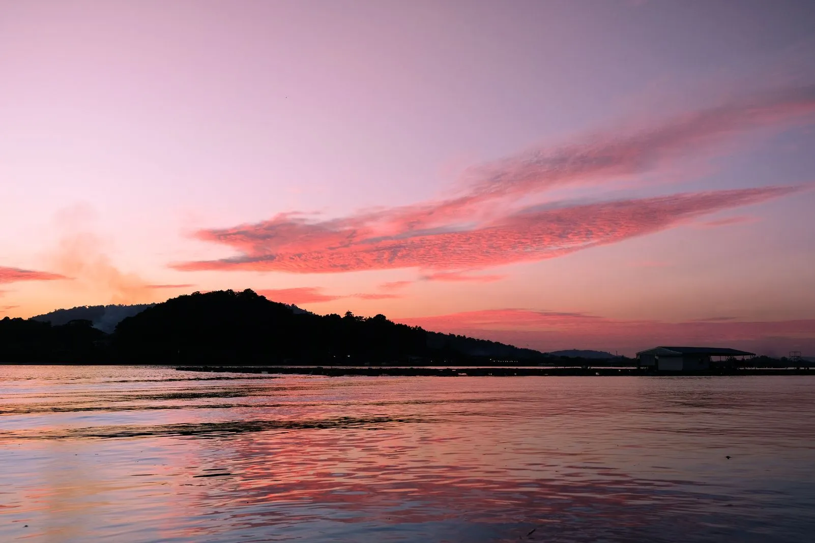 Vivid pink and orange sunset clouds reflected over calm water