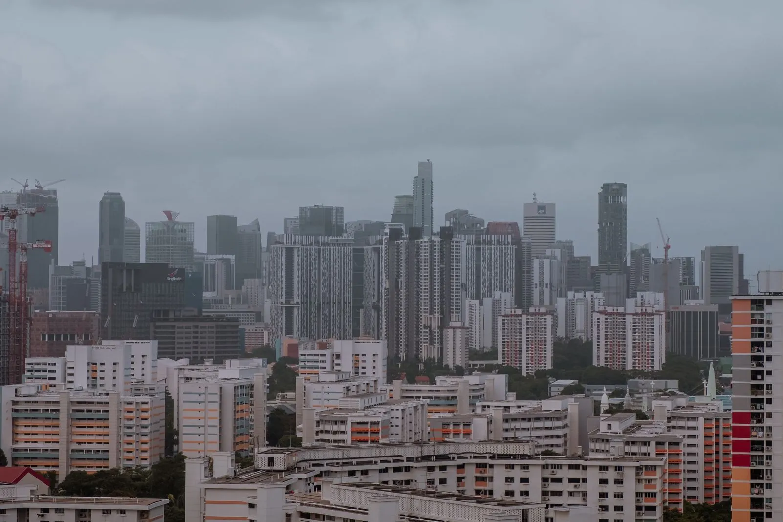 Overcast grey skyline with construction cranes towering over the high-rises