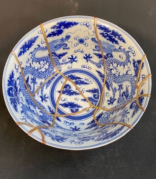Image of a white bowl with blue drawings mended together with gold