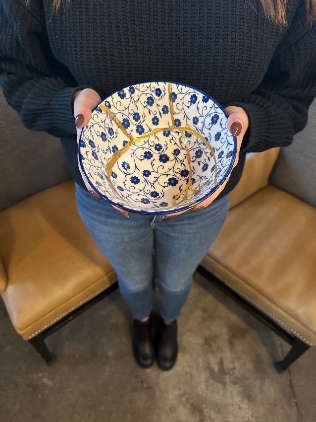 Image of a woman holding a blue and white bowl with gold lines running through it