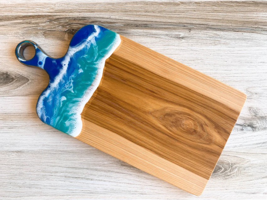 Image of a wooden cutting board with a resin wave design at the top and handle