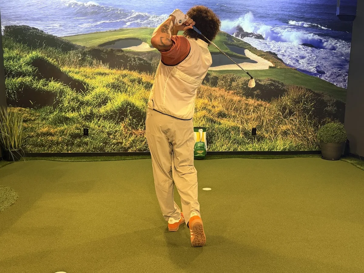 Golfer taking a swing in a Full Swing simulator bay at The Back Nine