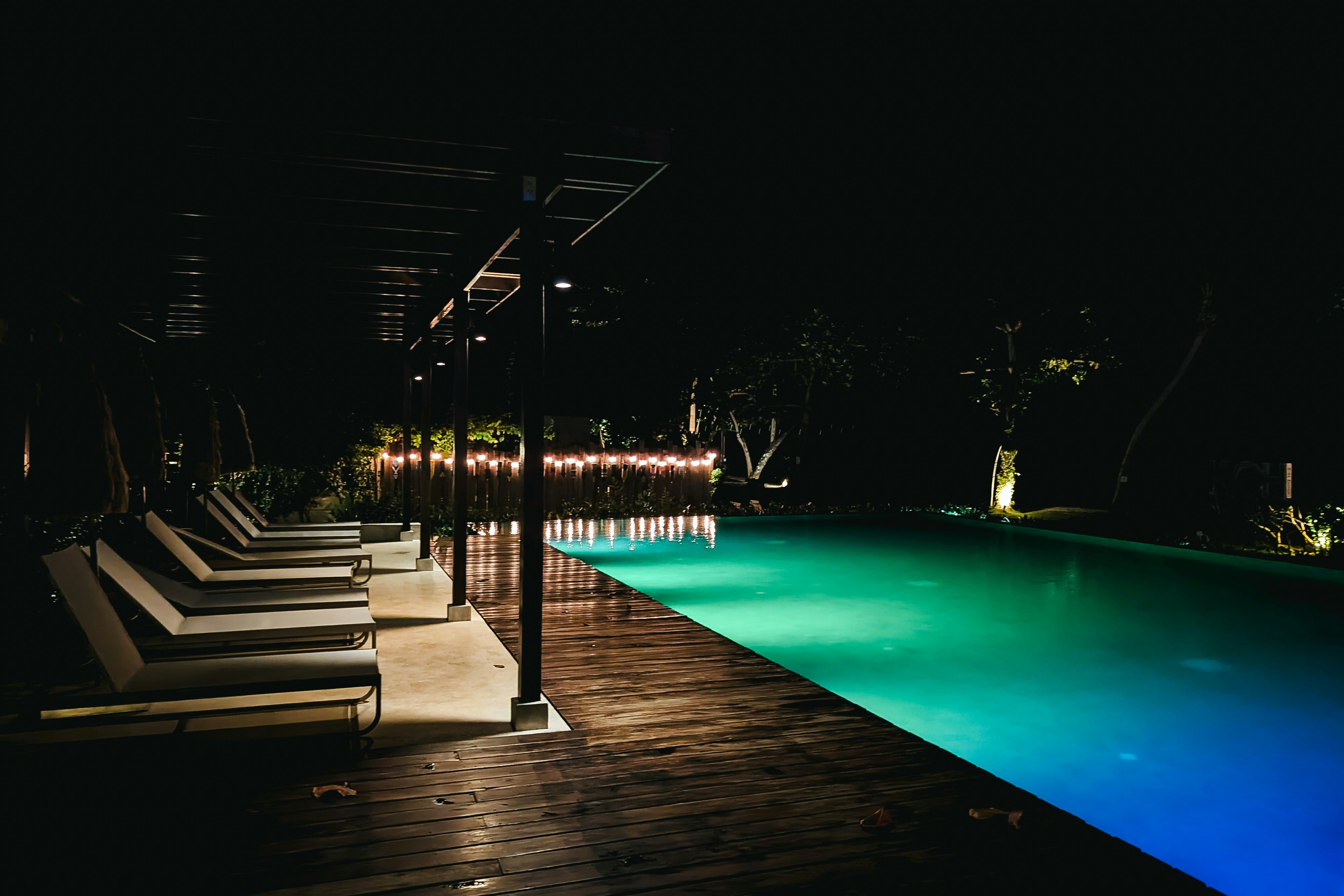 a-pool-at-night-with-lounge-chairs-around-it