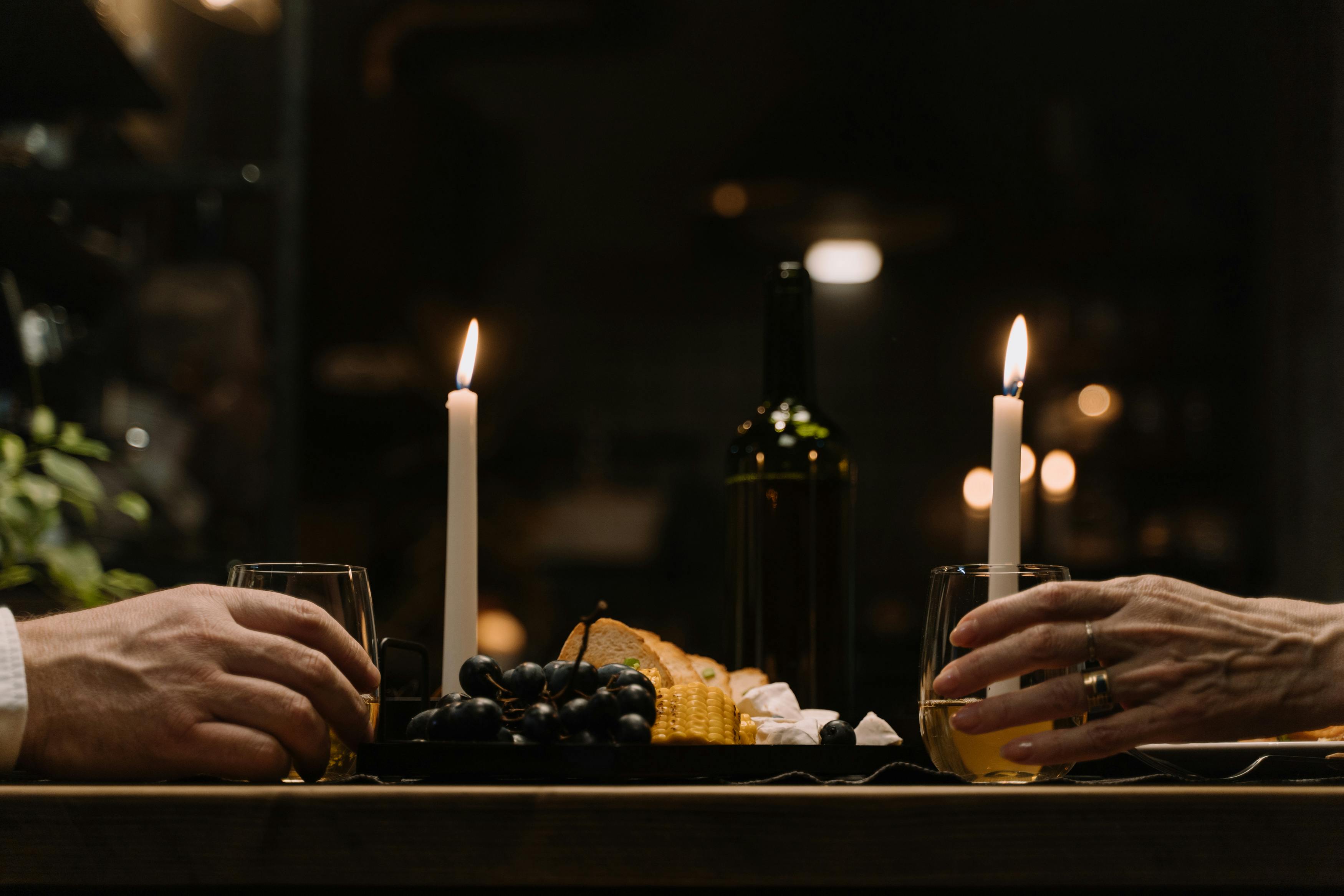 people-getting-the-glasses-of-drinks-on-the-table-with-lighted-candles-and-mouthwatering-food
