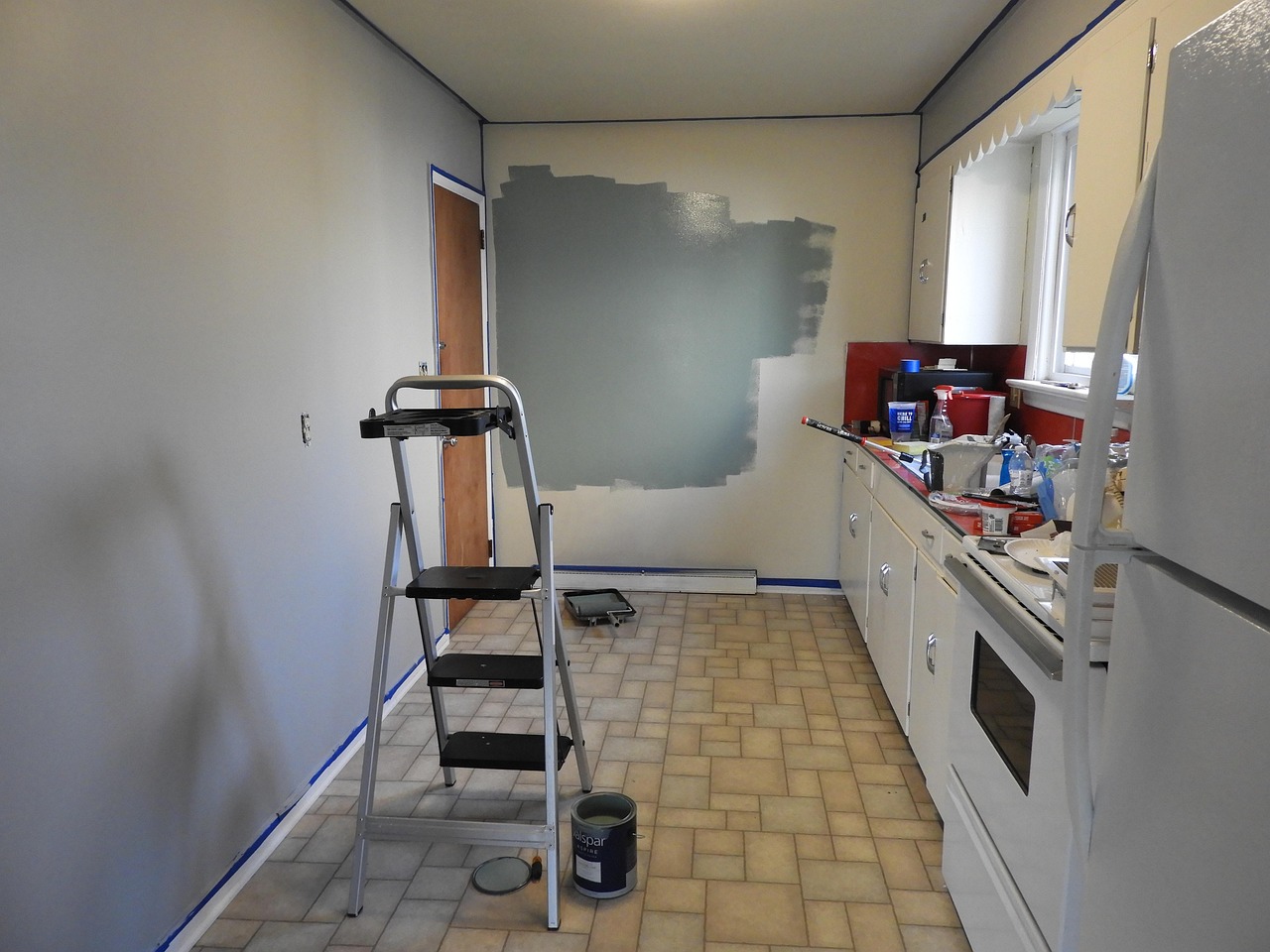 Persona che pittura una parete di bianco utilizzando rullo e nastro di carta.