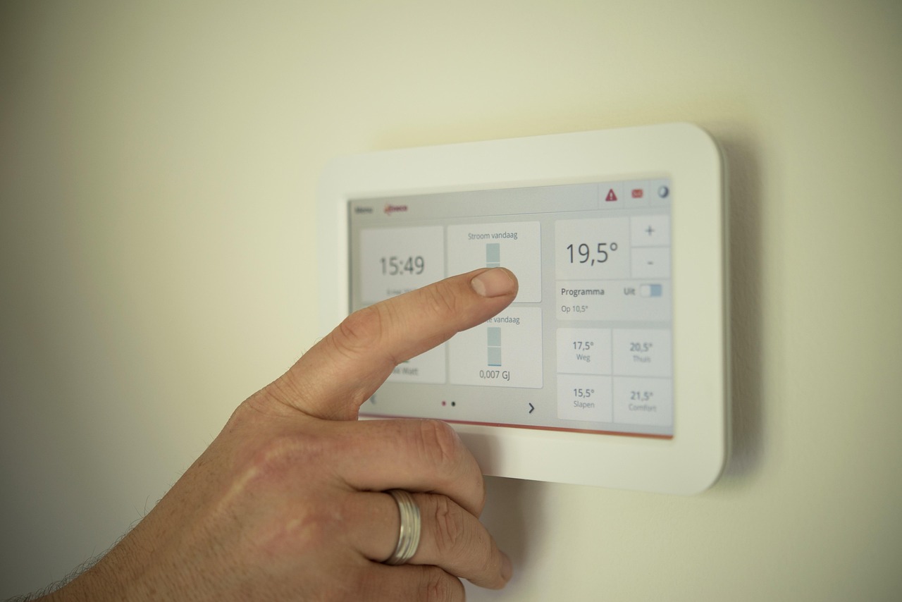 Hand adjusting a sleek smart thermostat mounted on an indoor wall to control home temperature.