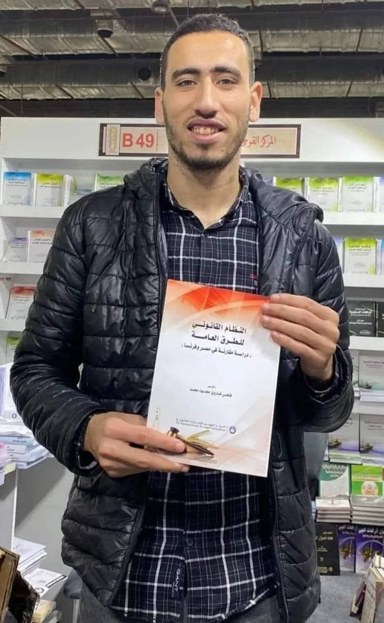 قارئ يحمل كتاب النظام القانوني للطرق العامة في جناح المركز القومي للإصدارات القانونية