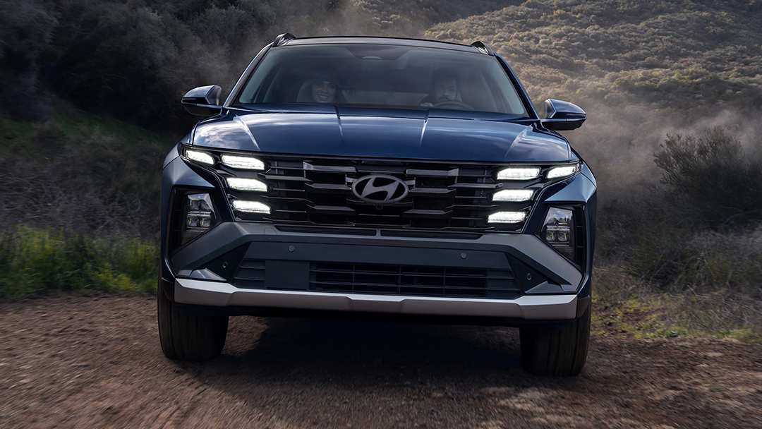 Vue 3/4 avant et latérale du hyundai tucson hybrid 2025 sur route de sable en pleine puissance
