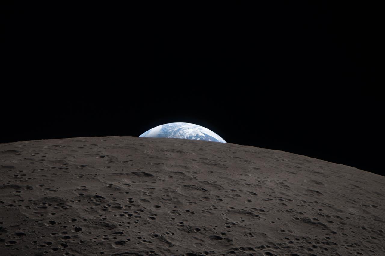 Earth rises above the cratered lunar surface as seen from the Artemis II Orion spacecraft during the lunar flyby on 6 April 2026