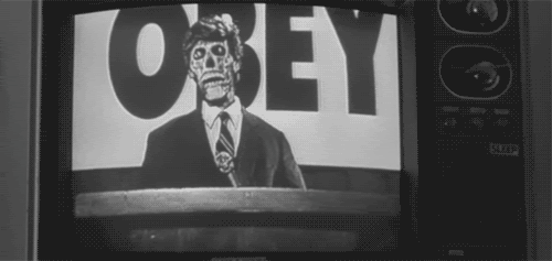 Scene from They Live film with politician in front of the word Obey