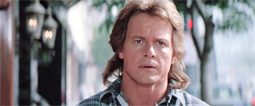 Roddy Piper in They Live film putting on glasses that reveal subliminal messages