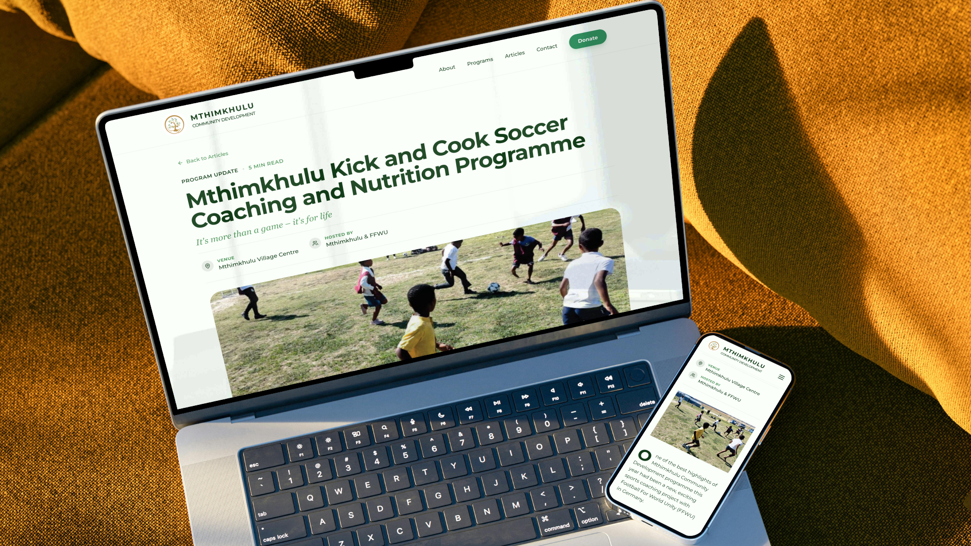 Laptop and mobile phone mockups displaying the Mthimkhulu sports coaching and nutrition program update article with a photo of children playing soccer.