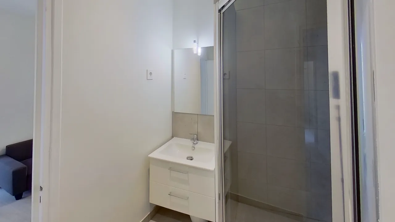 Salle de douche finie avec vasque, douche, wc et sèche serviettes.