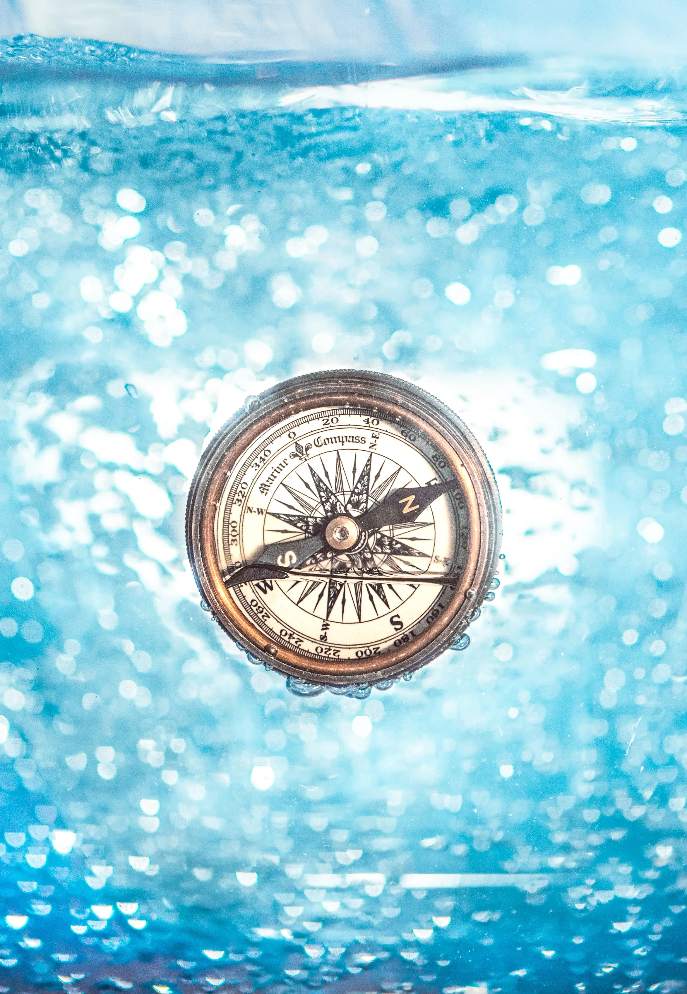 Old fashion compass (antique looking), on a blue watery background.