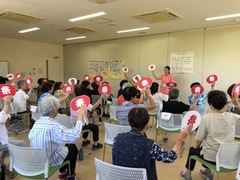 赤い道具を手に体操する参加者たち