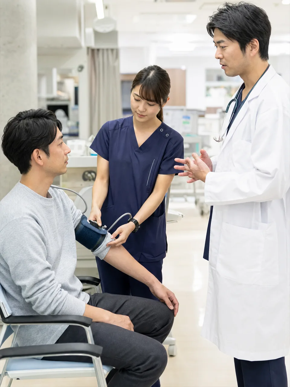 救急外来で対応する日本人医療スタッフ（自然な縦位置写真）。救急外来、トリアージ、医療チーム、病院の記事向け素材です。