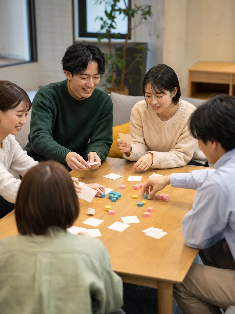 ボードゲームを楽しむ日本人の友達（自然な縦位置写真）。男女の友達、友情、ボードゲーム、交流の記事向け素材です。