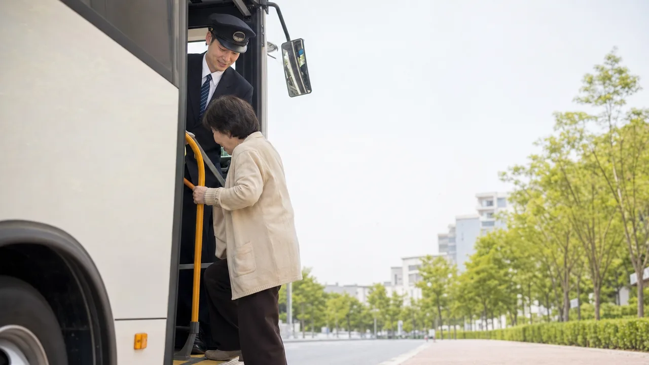 乗客を迎える日本人バス運転手（横長・コピースペース）。バス運転手、公共交通、バリアフリー、地域交通の記事向け素材です。