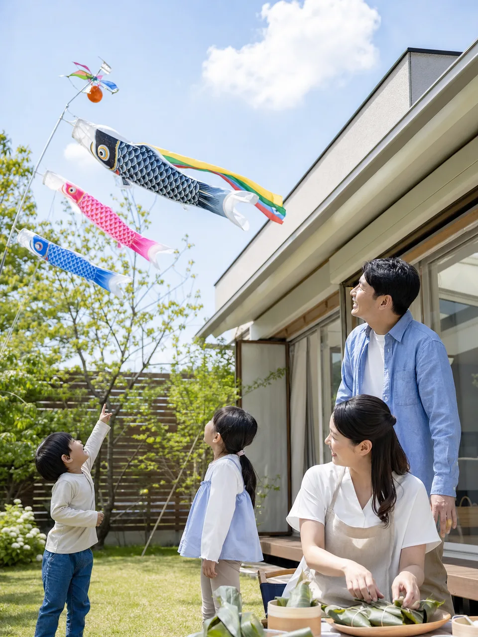 こどもの日を祝う日本人家族（自然な縦位置写真）。こどもの日、鯉のぼり、家族、春の行事の記事向け素材です。