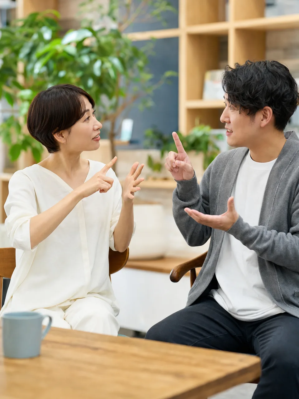 手話で会話する日本人（自然な縦位置写真）。手話、聴覚障害、コミュニケーション、共生の記事向け素材です。