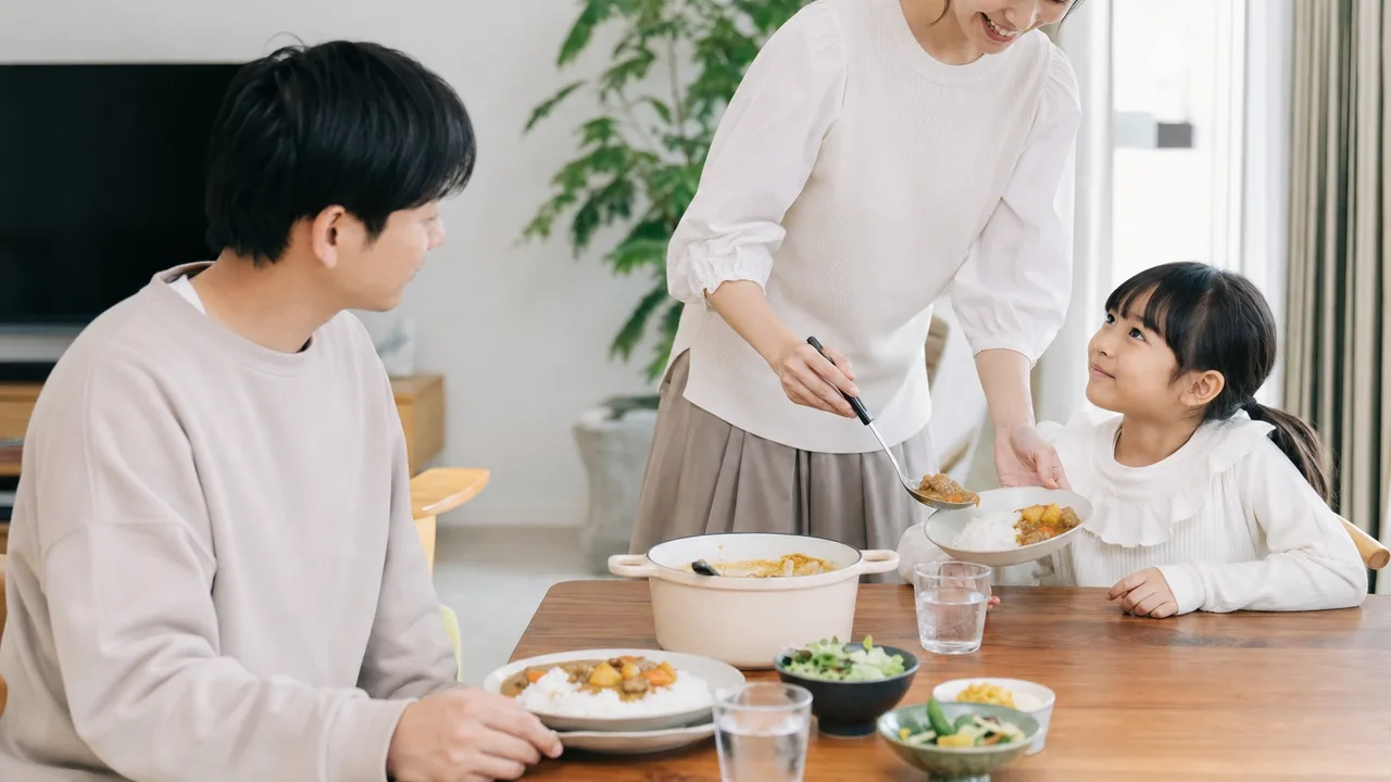 カレーライスを囲む日本人家族（横長・コピースペース）。カレーライス、家庭料理、家族、食卓の記事向け素材です。