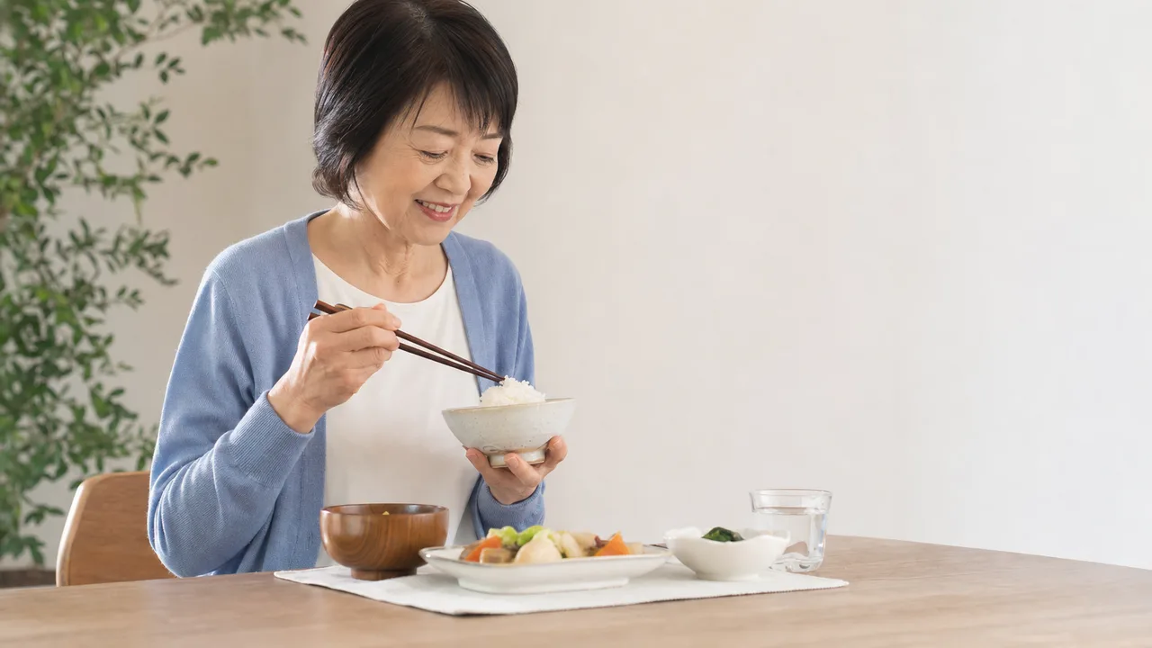 一人暮らしの日本人シニアの食卓（横長・コピースペース）。シニア一人暮らし、高齢者の食事、自立生活、一人ごはんの記事や案内に使える商用素材です。