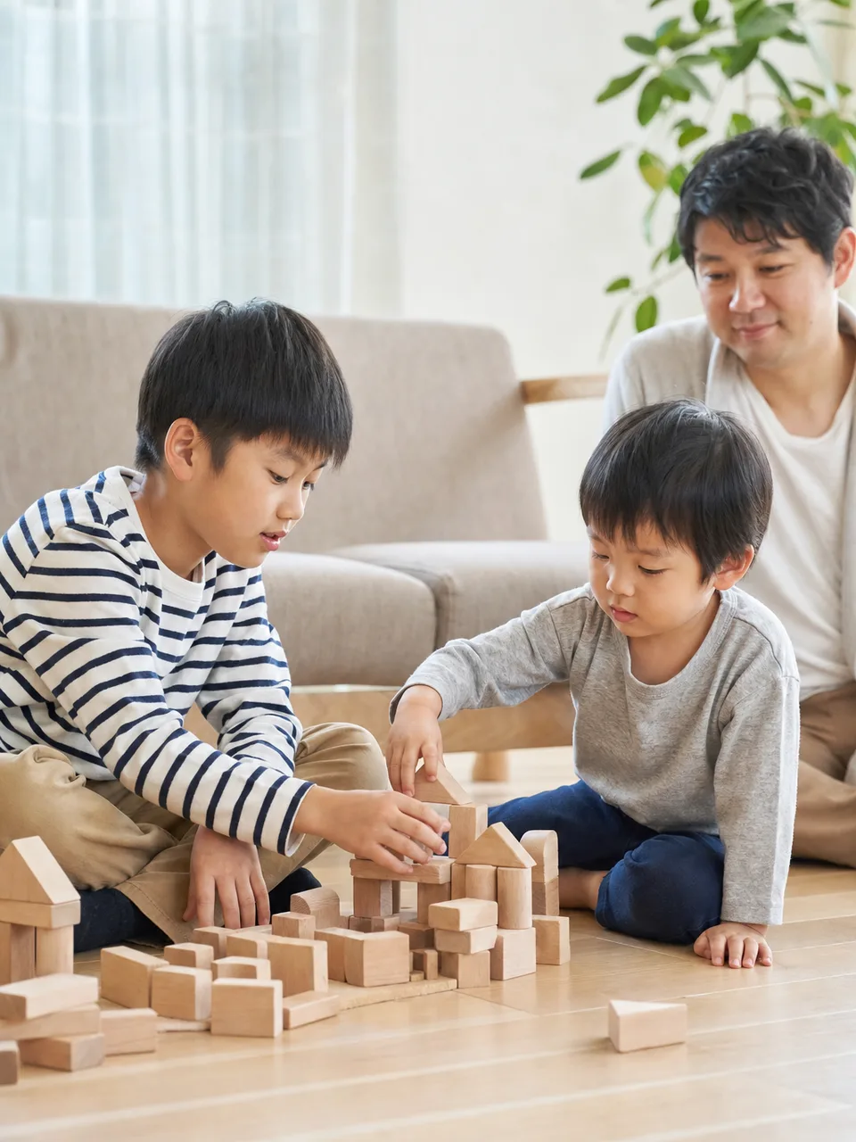 一緒に遊ぶ日本人の兄弟（自然な縦位置写真）。兄弟、きょうだい、子ども、協力をテーマにした記事向け素材です。