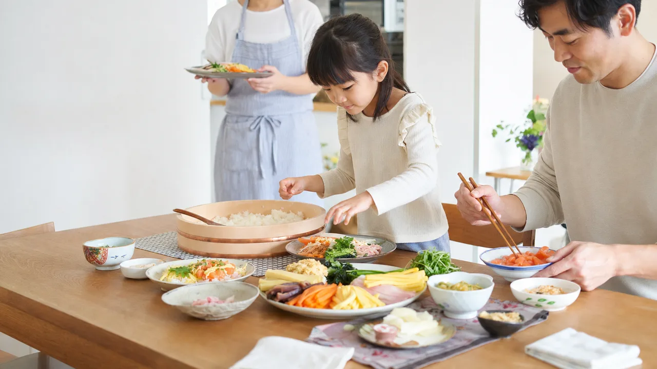 ちらし寿司を作る日本人家族（横長・コピースペース）。ちらし寿司、祝いの食卓、親子料理、和食の記事向け素材です。