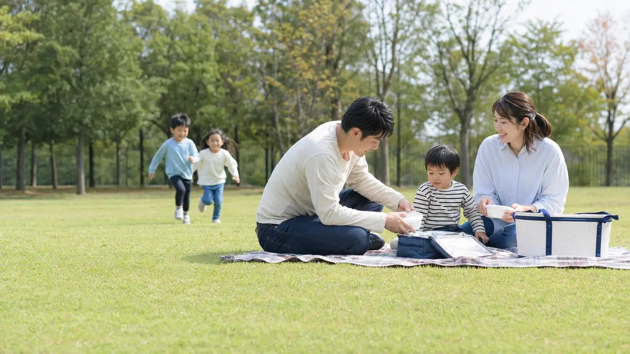 週末のピクニックを楽しむ日本人（横長・コピースペース）。週末ピクニック、家族、レジャー、公園の記事向け素材です。