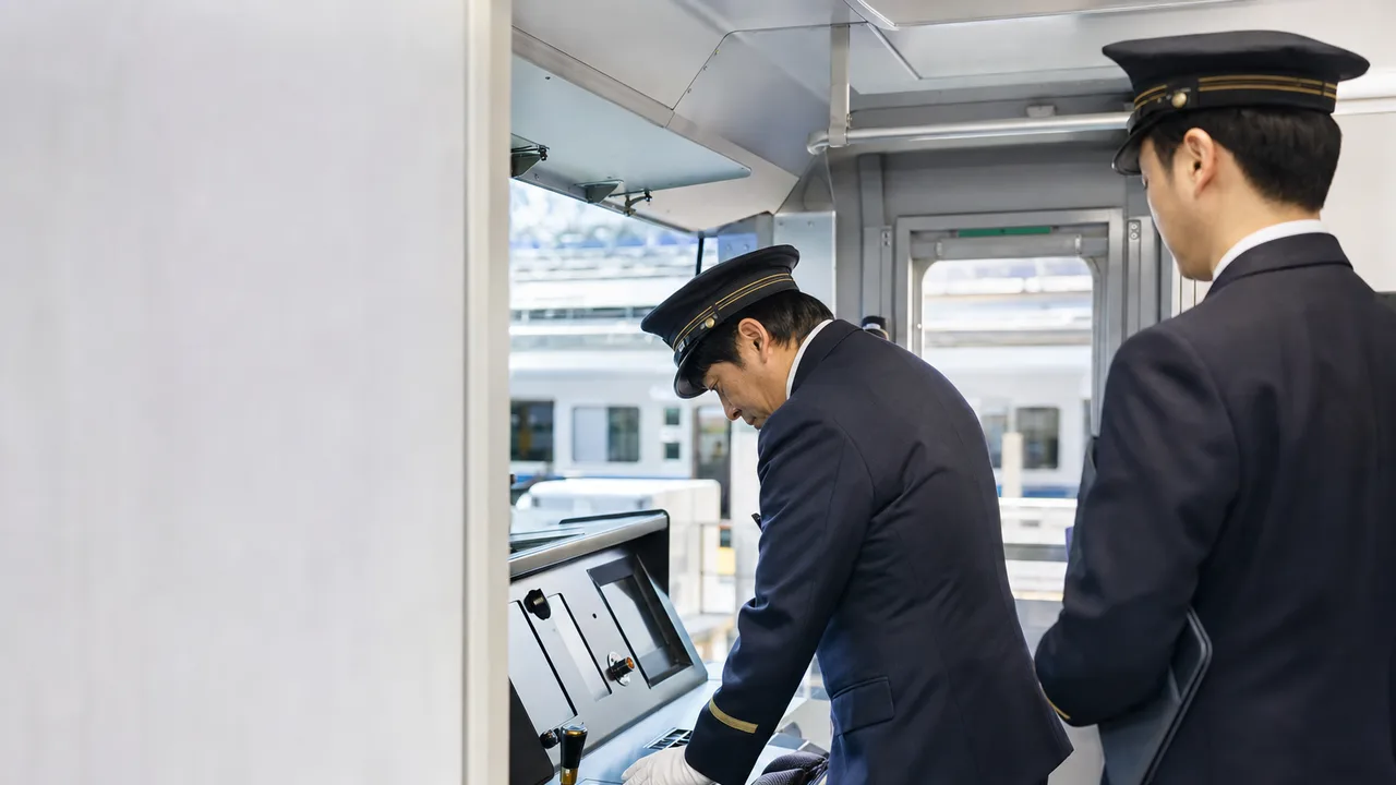 運行前点検をする日本人電車運転士（横長・コピースペース）。電車運転士、鉄道、安全運行、公共交通の記事に使える素材です。