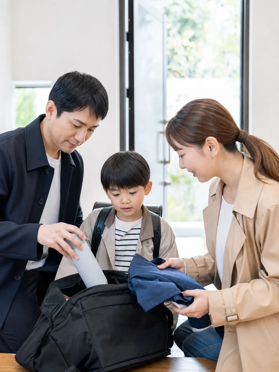 登校準備を協力する日本人の親（自然な縦位置写真）。登校準備、共同育児、子育て、共働き家庭の記事や案内に使える商用素材です。