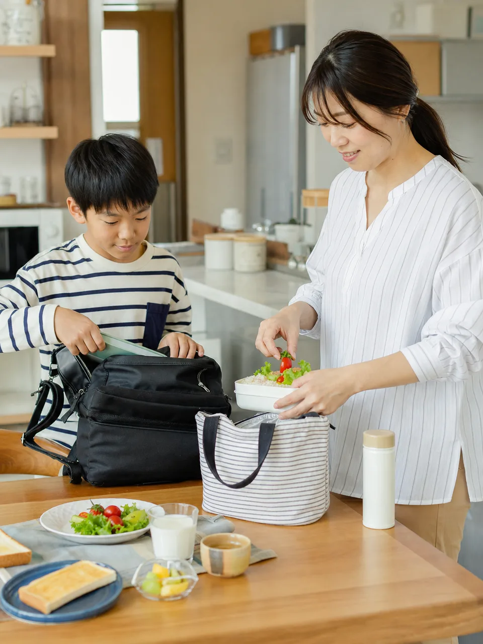 朝の支度をする日本人ひとり親家庭（自然な縦位置写真）。ひとり親、一人親家庭、子育て、朝の暮らしの記事向け素材です。