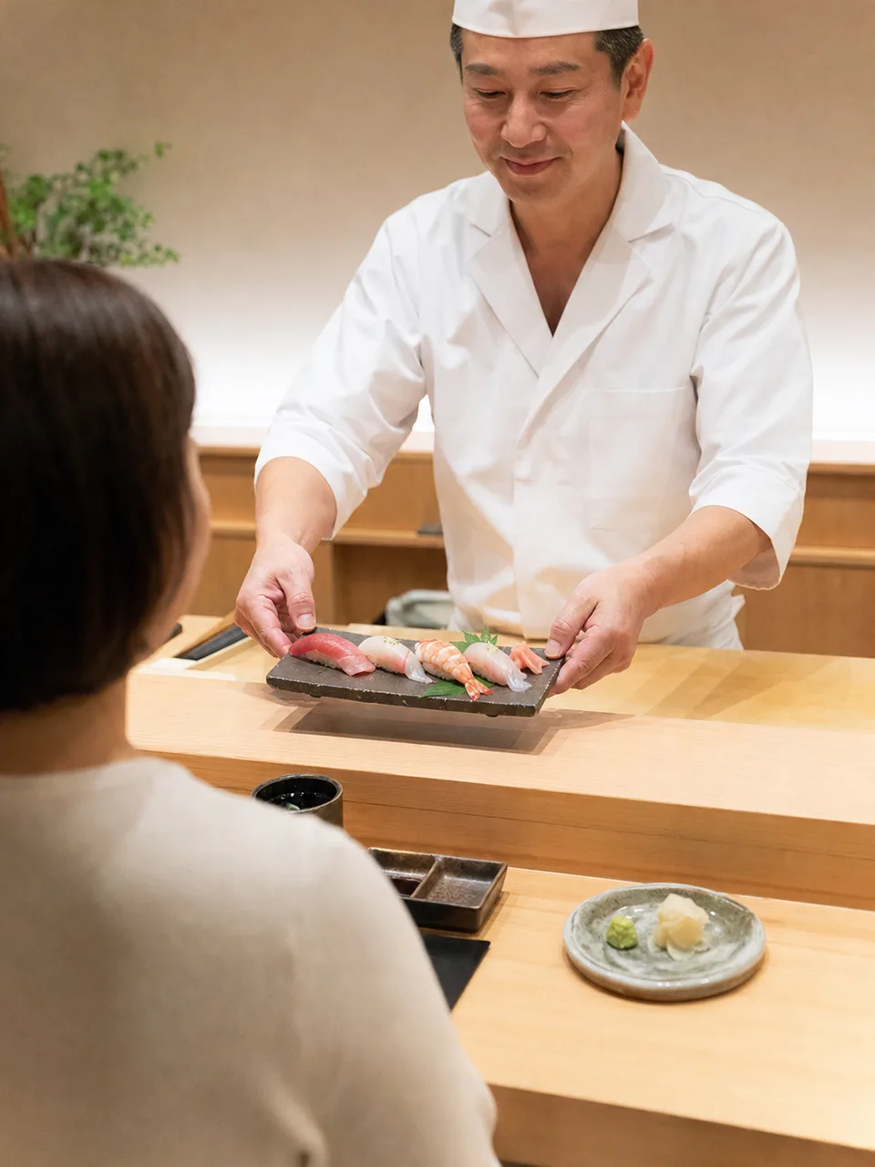 寿司を握る日本人職人（自然な縦位置写真）。寿司、日本料理、職人、飲食店の紹介に使える調理場面です。