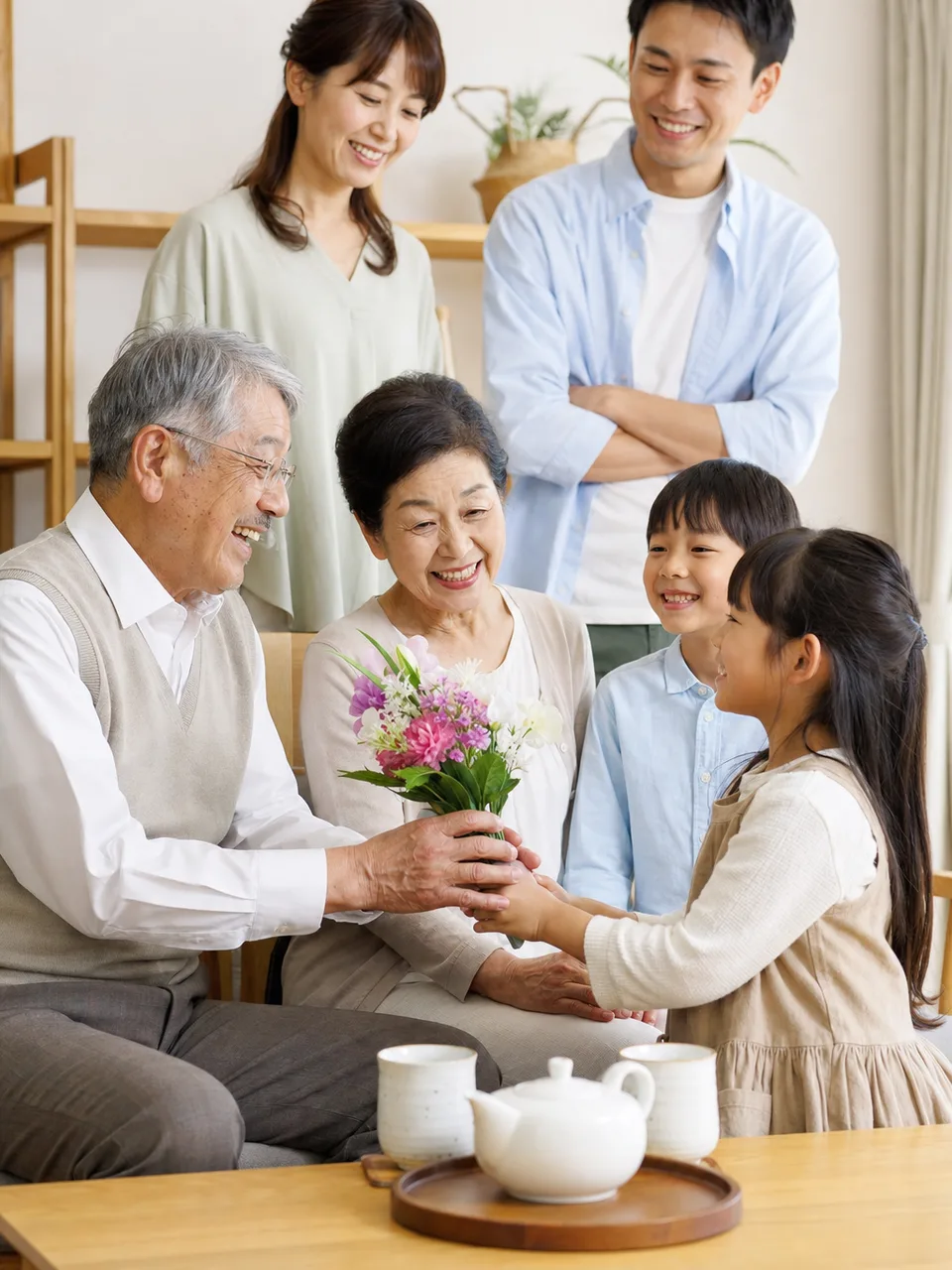 敬老の日を祝う日本人家族（自然な縦位置写真）。敬老の日、三世代交流、家族サービスの案内に使える素材です。