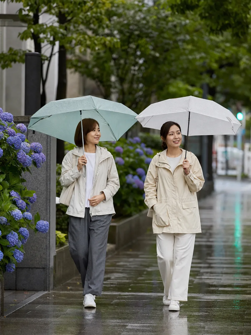 梅雨の街を歩く日本人（自然な縦位置写真）。梅雨、雨、通勤、暮らしの記事に使える季節素材です。
