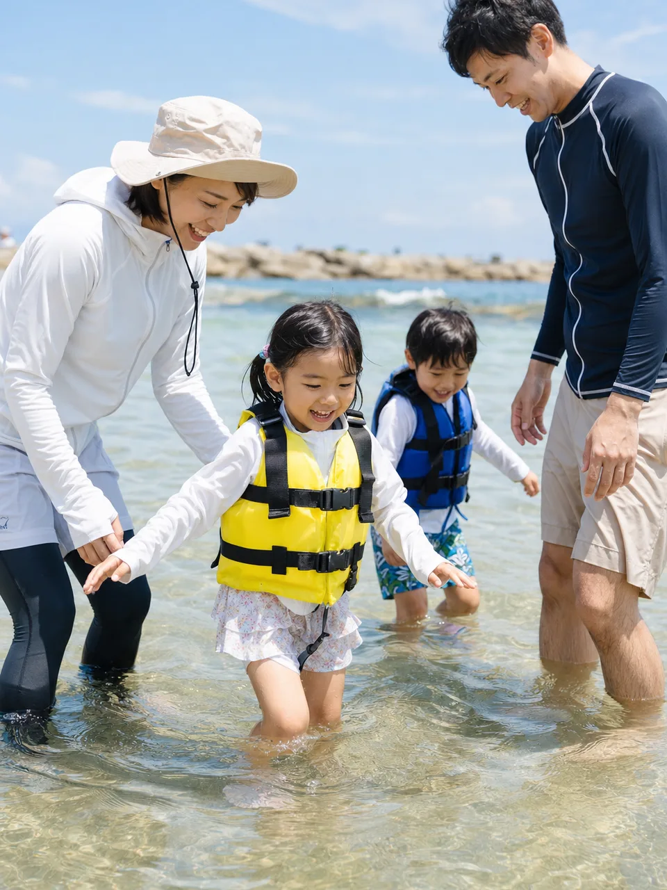 海水浴を楽しむ日本人家族（自然な縦位置写真）。海水浴、夏休み、家族旅行、海の安全啓発に使える素材です。