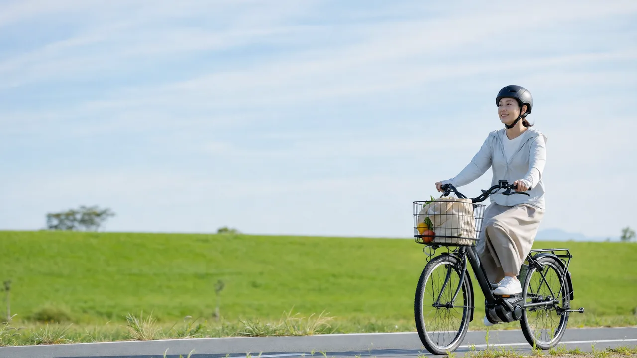 電動自転車で買い物に行く日本人（横長・コピースペース）。電動自転車で買い物、電動アシスト自転車、自転車の買い物、ヘルメットの記事や案内に使える商用素材です。