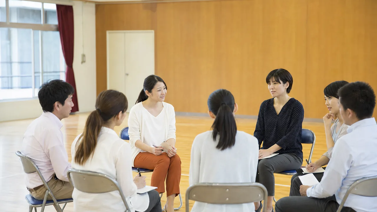 学校について話し合う日本人PTA（横長・コピースペース）。PTA、保護者会、学校運営、地域連携の記事に使える素材です。